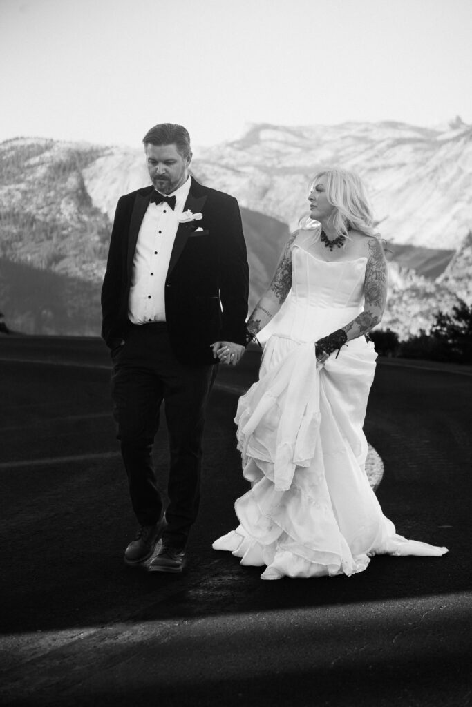 A couple walking down a road during their Glacier Point Elopement captured by an Yosemite Elopement Photographer who does Yosemite Elopement Photography